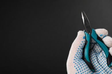 Photo of Man with bent nose pliers on black background, closeup. Space for text