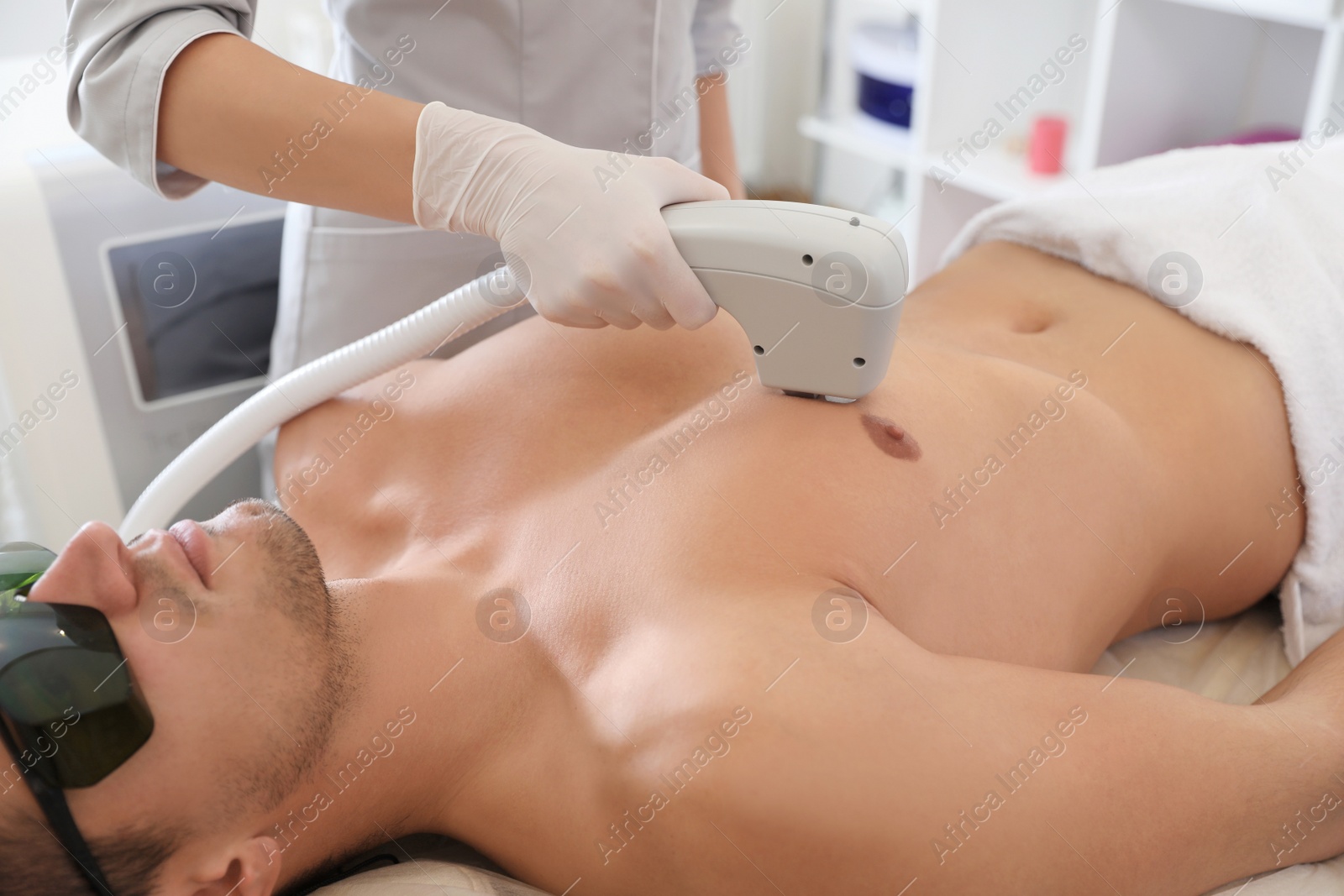 Photo of Young man undergoing laser epilation procedure in beauty salon, closeup