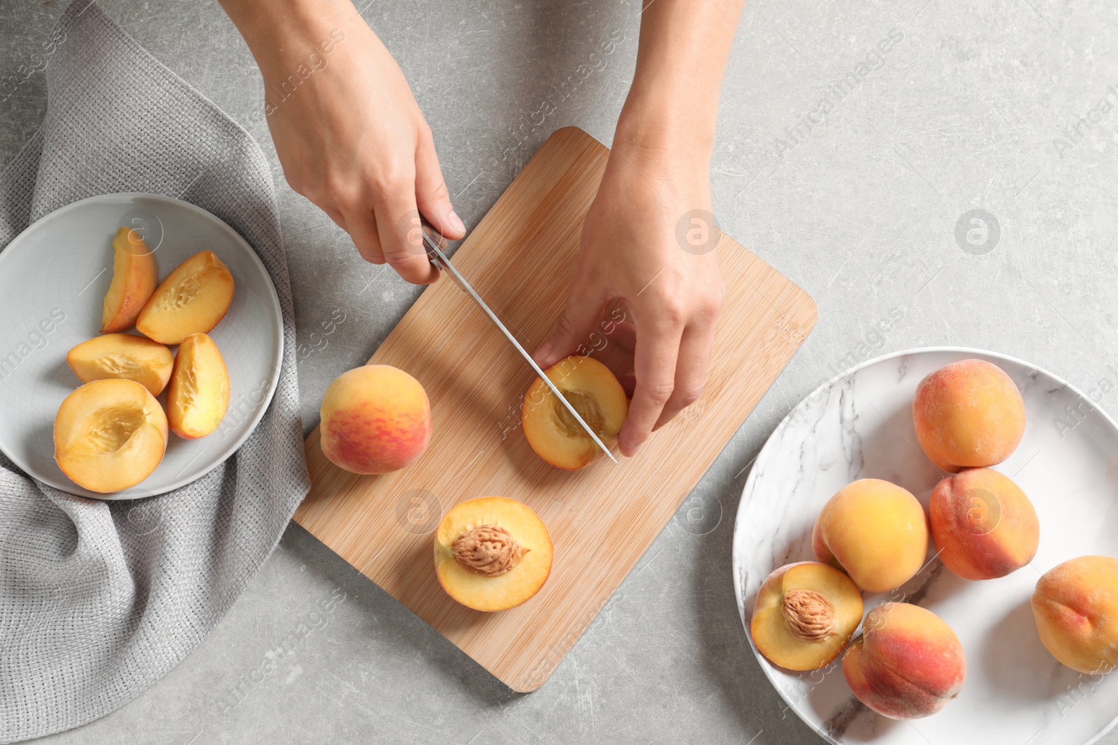 Photo of Woman cutting fresh sweet peaches on table, top view