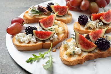 Bruschettas with cheese, figs and blackberries served on table