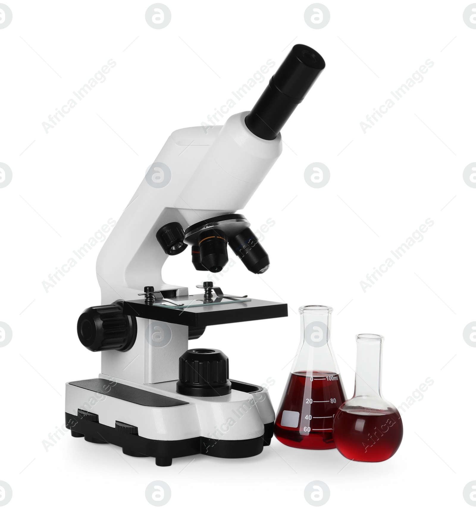 Photo of Laboratory glassware with red liquid and microscope isolated on white