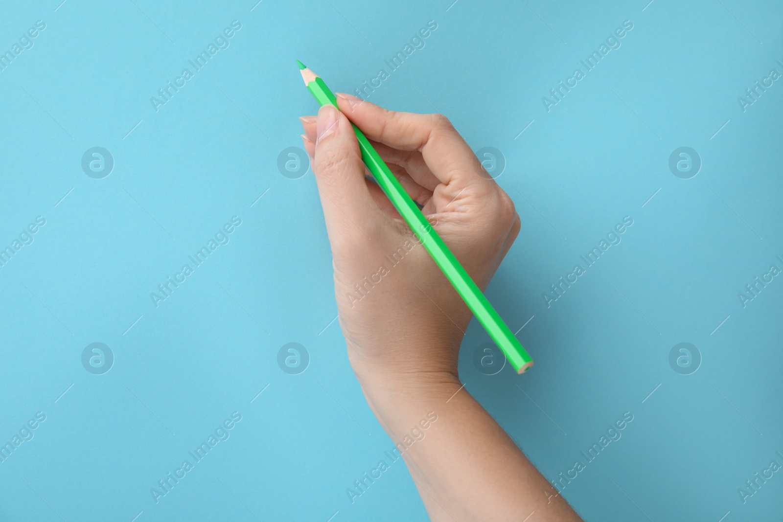 Photo of Woman with green pencil on light blue background, closeup