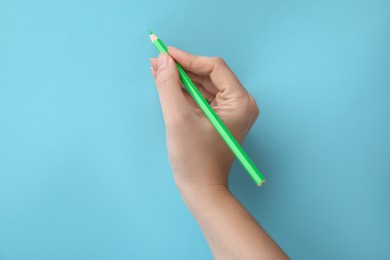 Photo of Woman with green pencil on light blue background, closeup