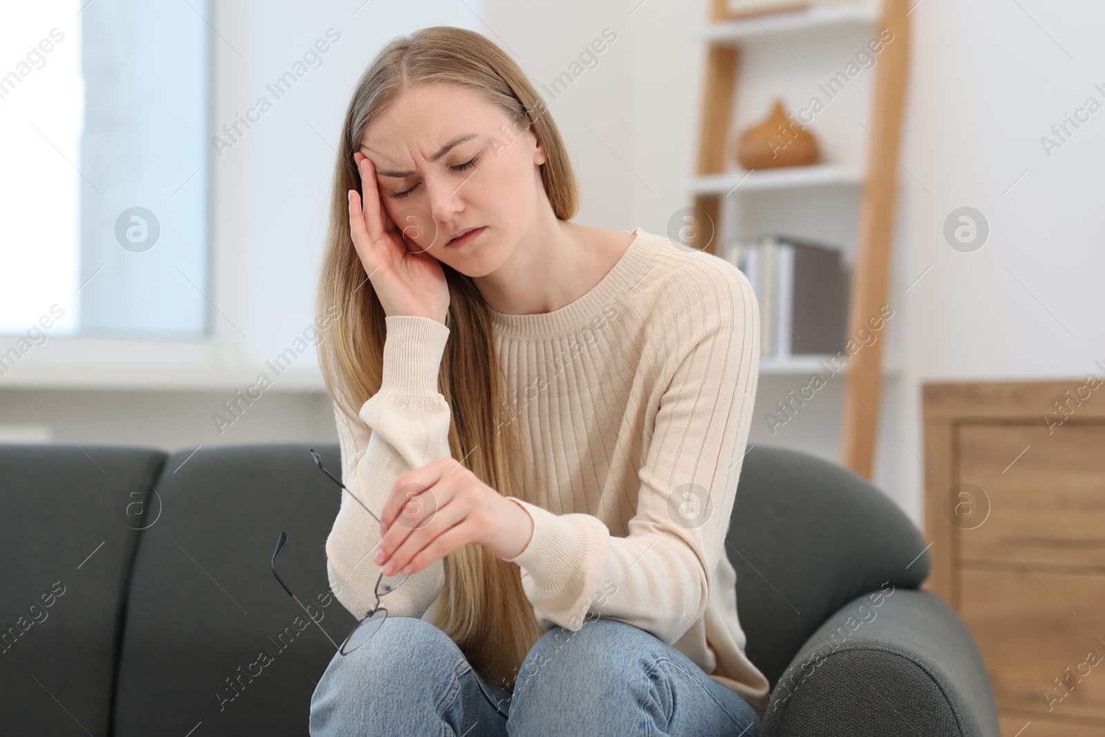 Photo of Overwhelmed young woman with glasses suffering from headache at home