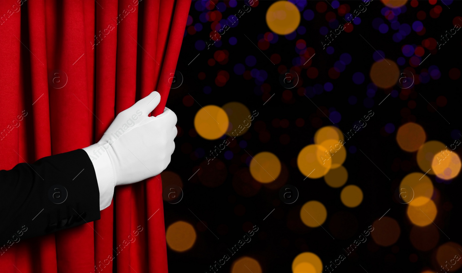 Image of Man opening red front curtain against blurred lights. Bokeh effect 