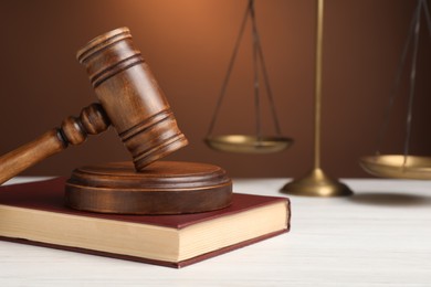 Photo of Wooden gavel and book on white table, space for text. Law concept