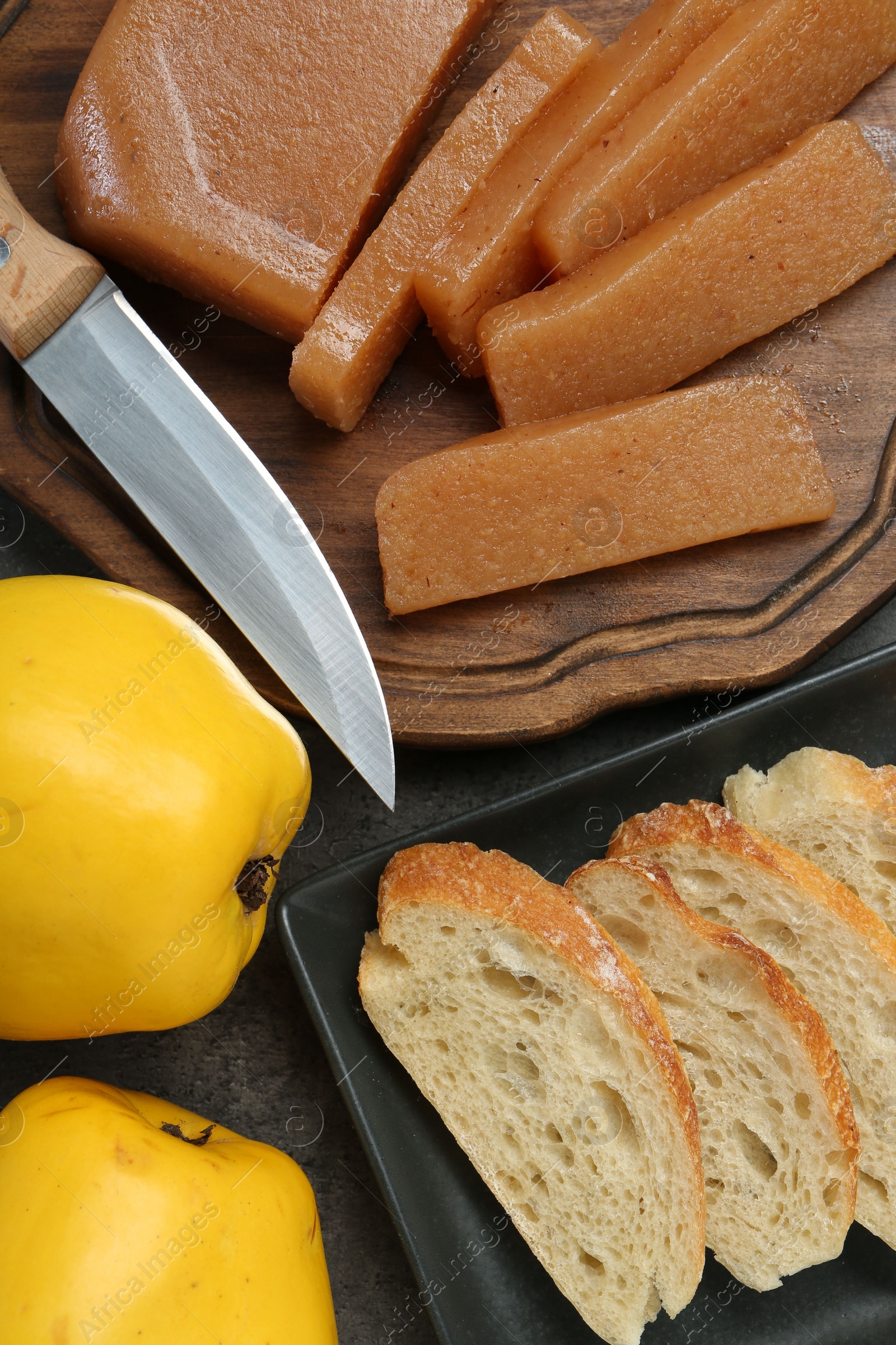 Photo of Delicious quince paste, bread, butter and fresh fruits on grey table, flat lay