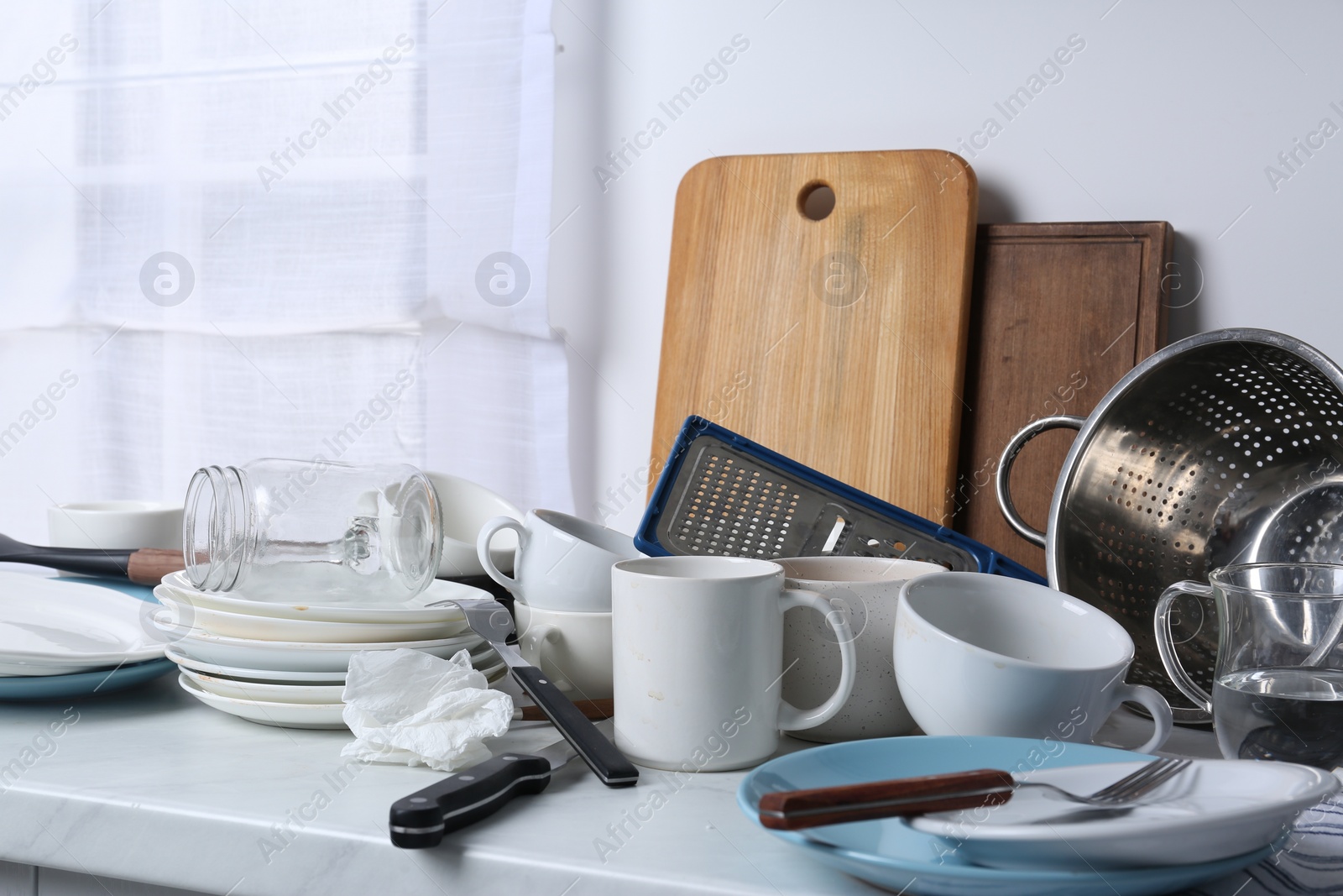 Photo of Many dirty utensils and dishware on countertop in messy kitchen