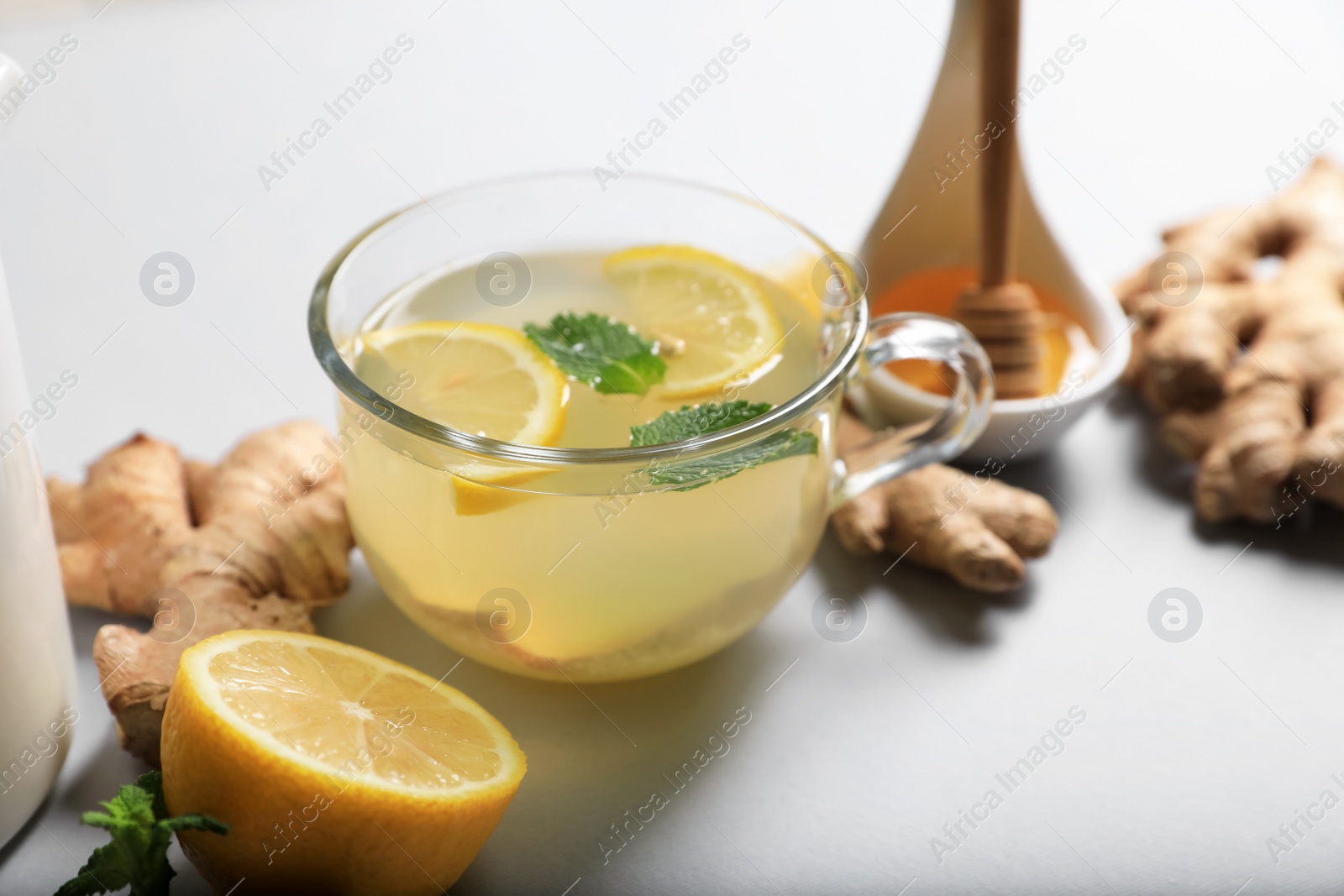 Photo of Delicious ginger tea and ingredients on light grey background