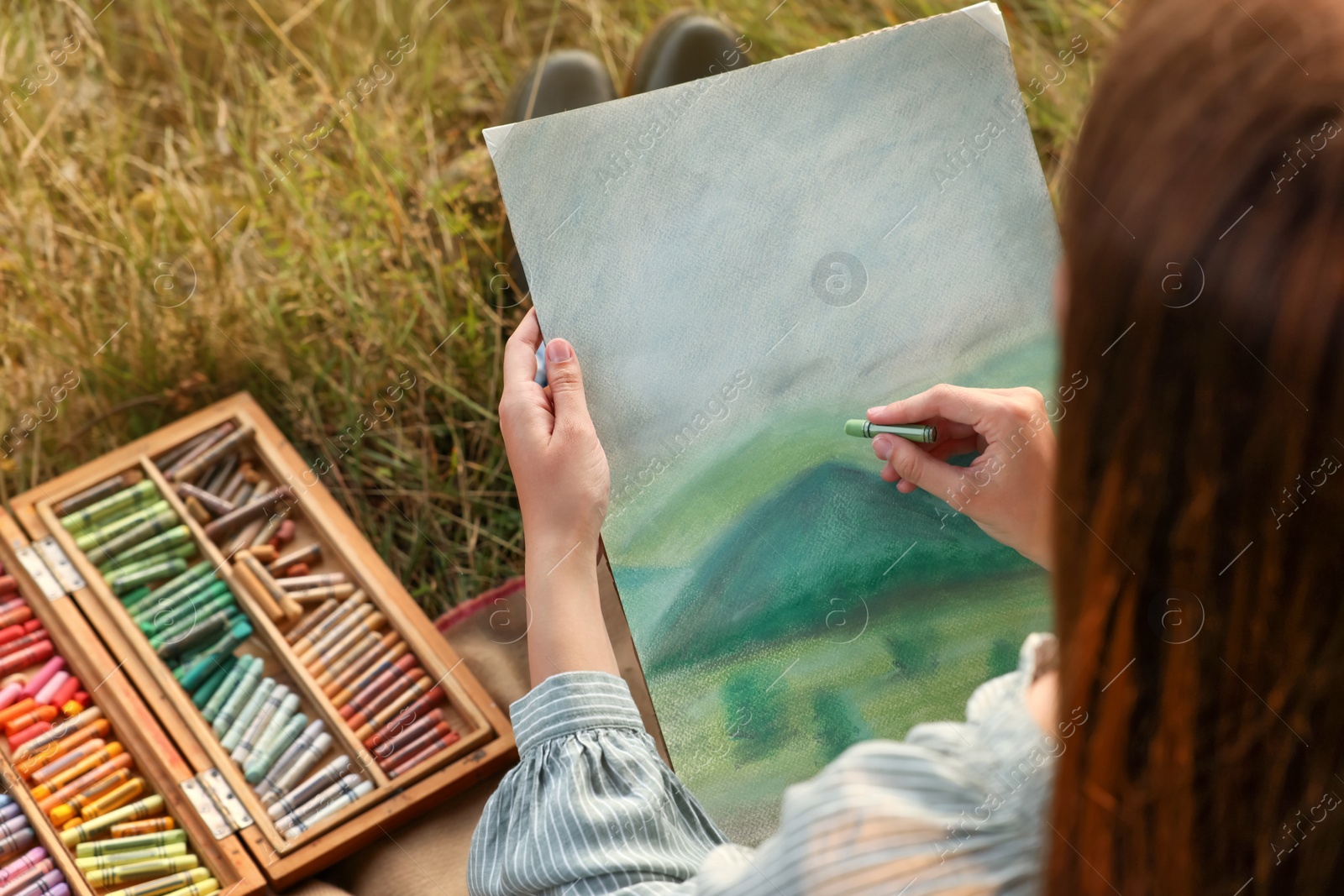 Photo of Woman drawing landscape with soft pastels outdoors, closeup