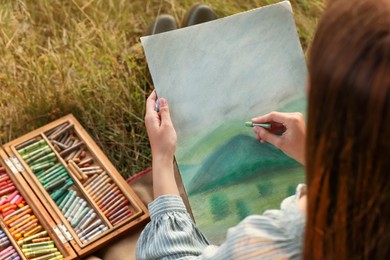 Photo of Woman drawing landscape with soft pastels outdoors, closeup