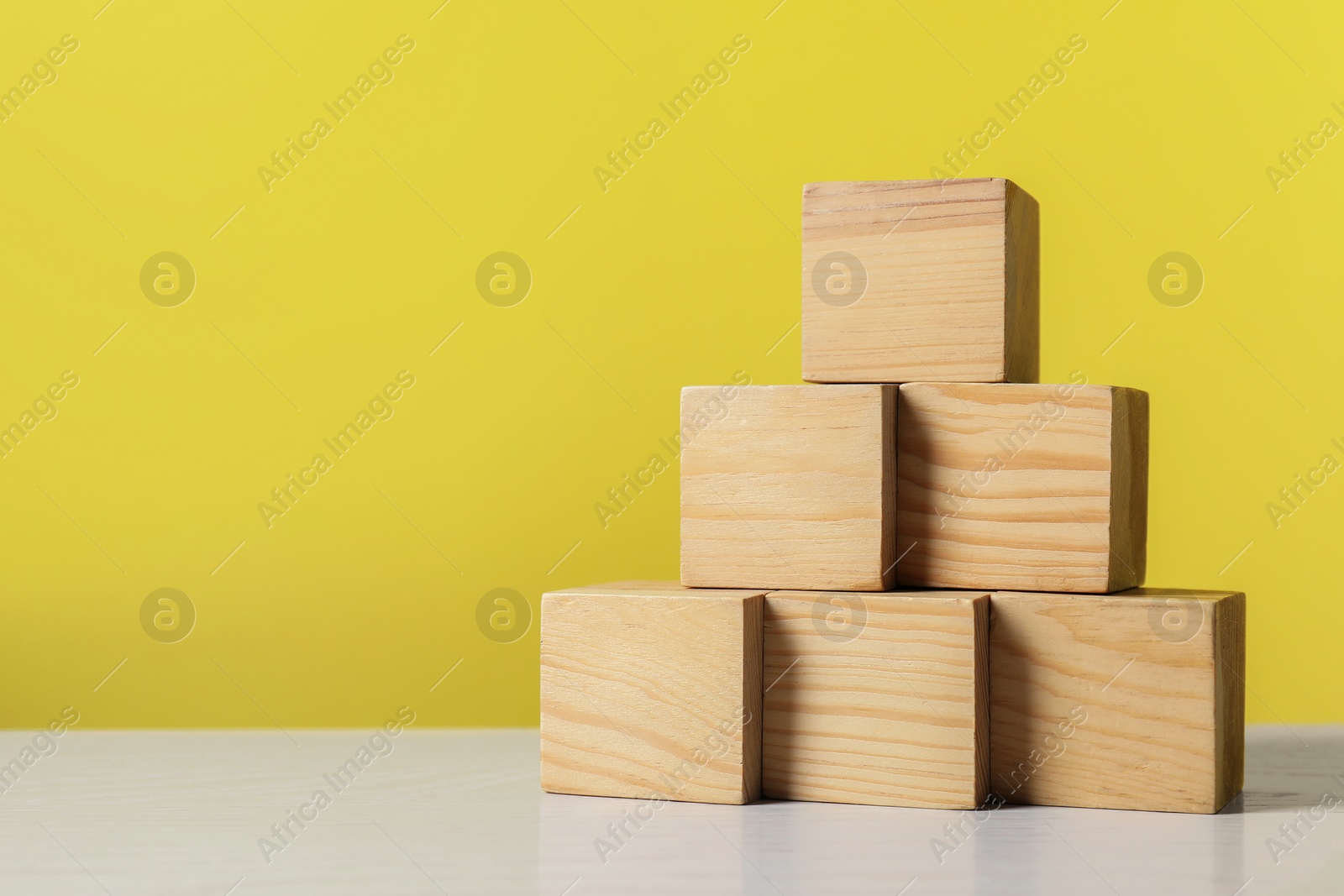 Photo of Pyramid of blank cubes on white wooden table. Space for text