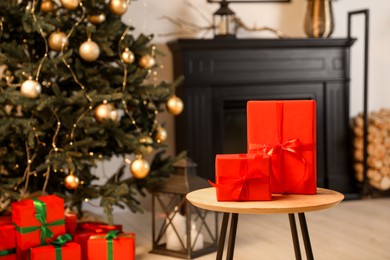 Photo of Beautifully wrapped Christmas gifts on wooden table in living room, space for text