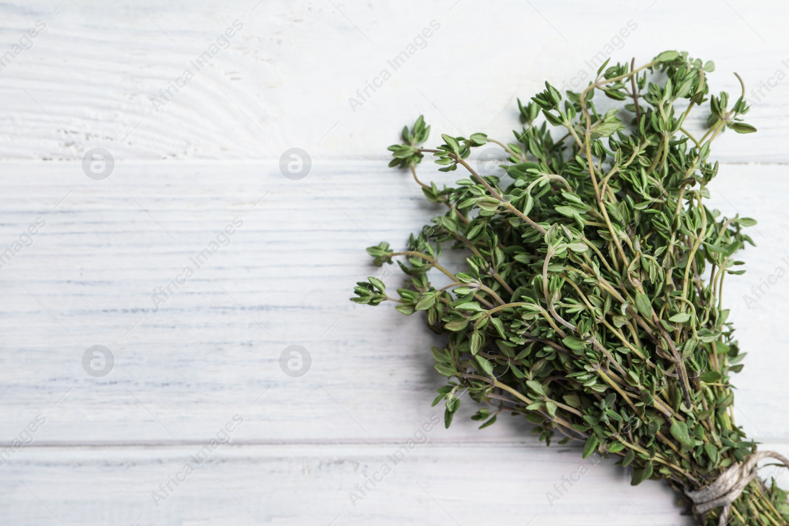 Photo of Bunch of aromatic thyme on white wooden table, top view. Space for text