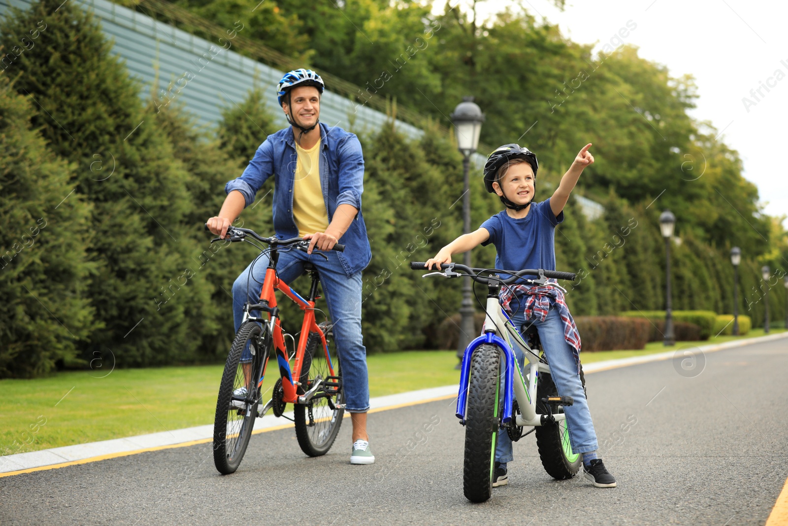 Photo of Dad and son riding modern bicycles outdoors