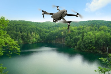 Image of Modern drone flying over picturesque lake near mountains. Aerial survey