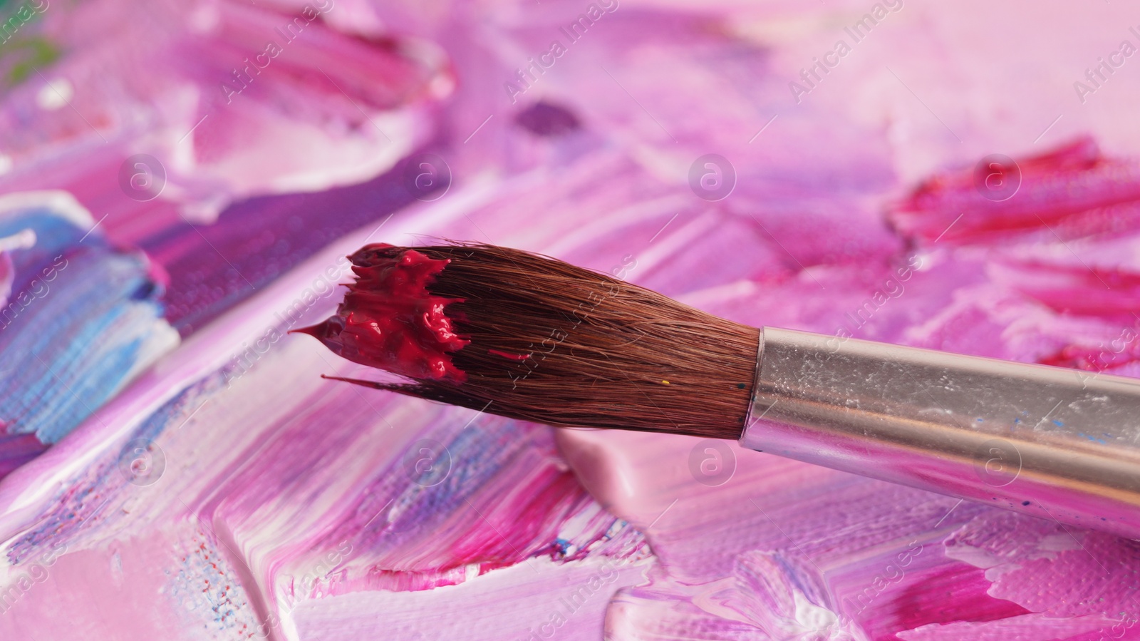 Photo of Brush on canvas with mixed bright paints, closeup