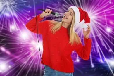 Happy woman in Santa hat singing on bright background