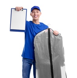 Photo of Dry-cleaning delivery. Happy courier holding garment cover with clothes and clipboard on white background