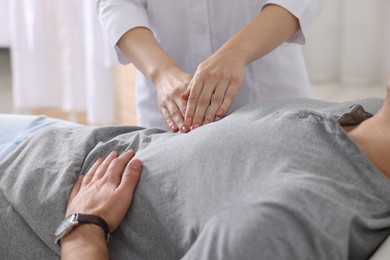 Gastroenterologist examining patient with stomach pain in clinic, closeup