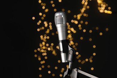 Stand with microphone against black background with blurred lights. Sound recording and reinforcement