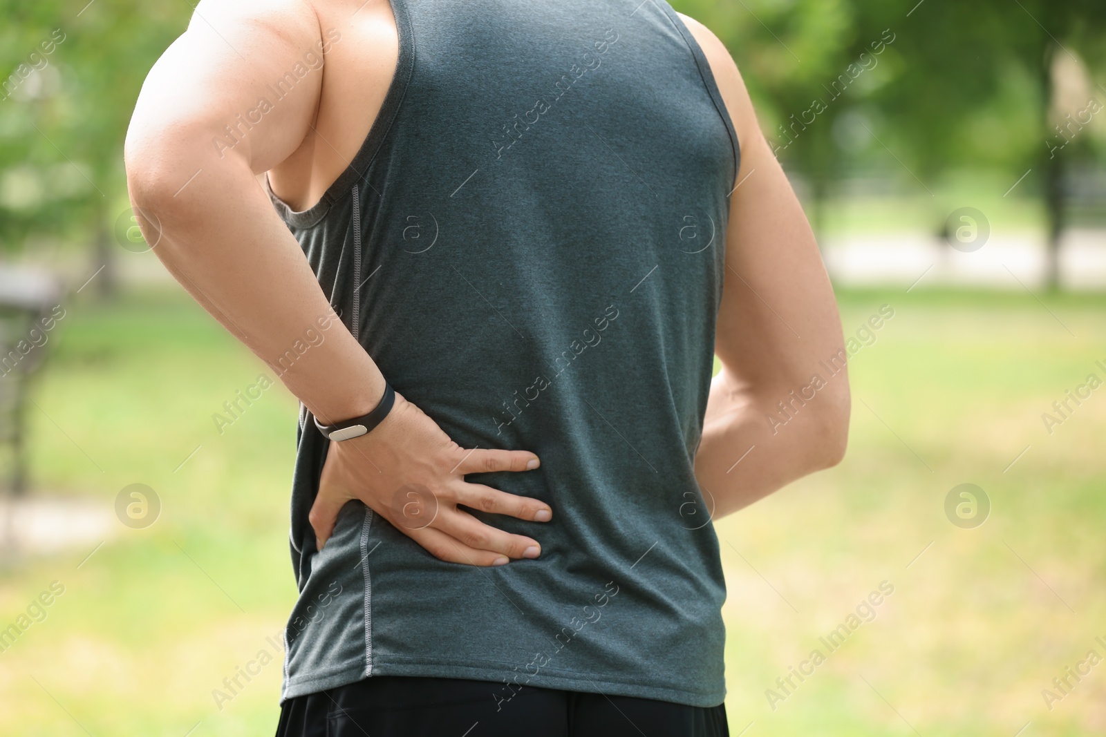 Photo of Man in sportswear suffering from back pain outdoors