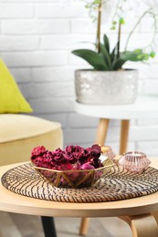 Aromatic potpourri of dried flowers in bowl and burning candles on wooden table indoors