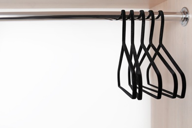 Photo of Clothes hangers on metal rail in wardrobe