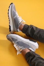 Photo of Man wearing stylish sneakers on yellow background, closeup