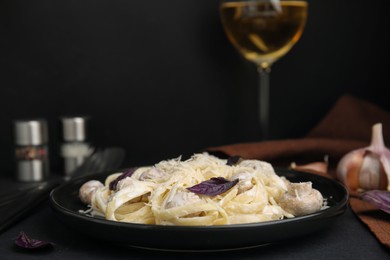 Photo of Delicious pasta with mushrooms on black table, closeup