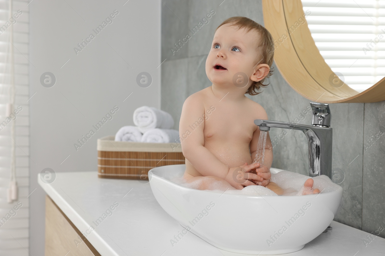 Photo of Cute little baby bathing in sink at home