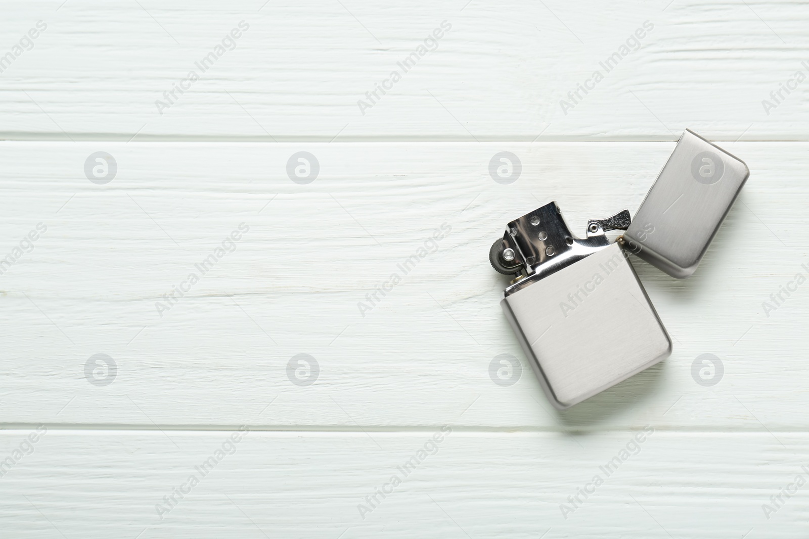 Photo of Gray metallic cigarette lighter on white wooden table, top view. Space for text