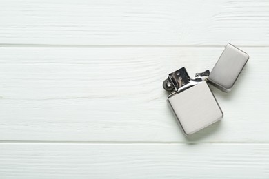 Photo of Gray metallic cigarette lighter on white wooden table, top view. Space for text