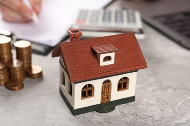 Photo of Woman planning budget at grey table, focus on house model