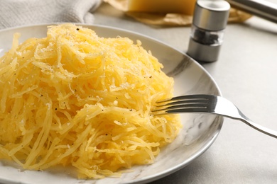 Plate with cooked spaghetti squash on gray table
