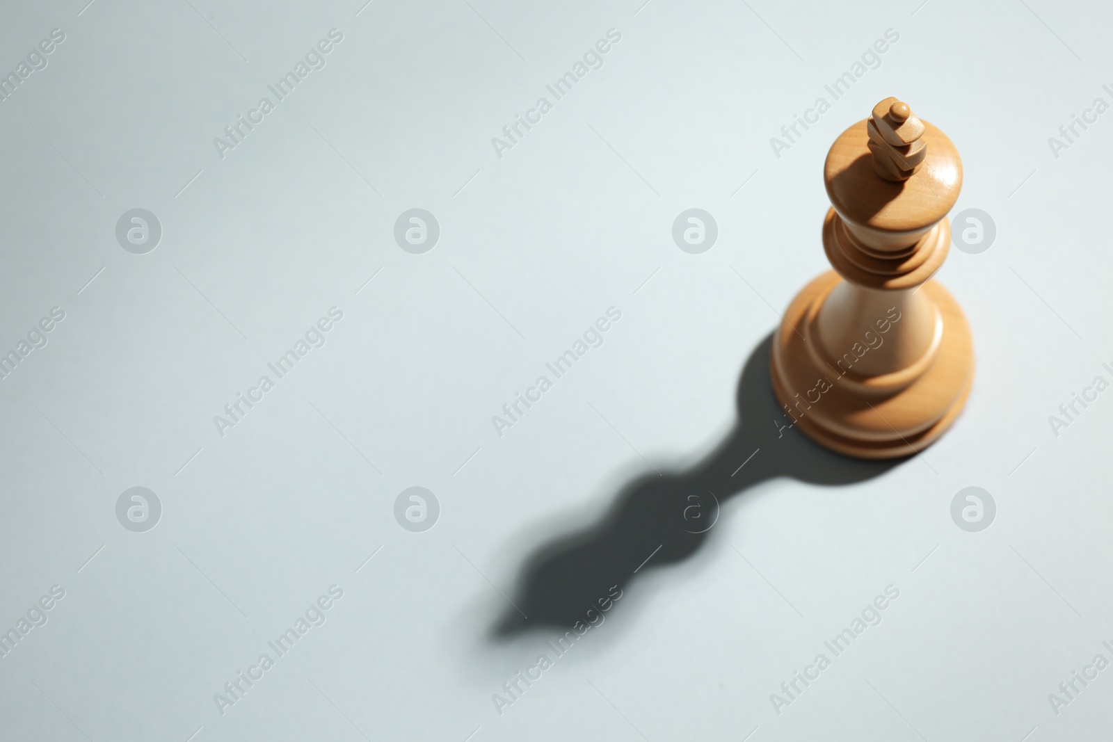 Photo of White wooden chess king on light grey background, above view. Space for text