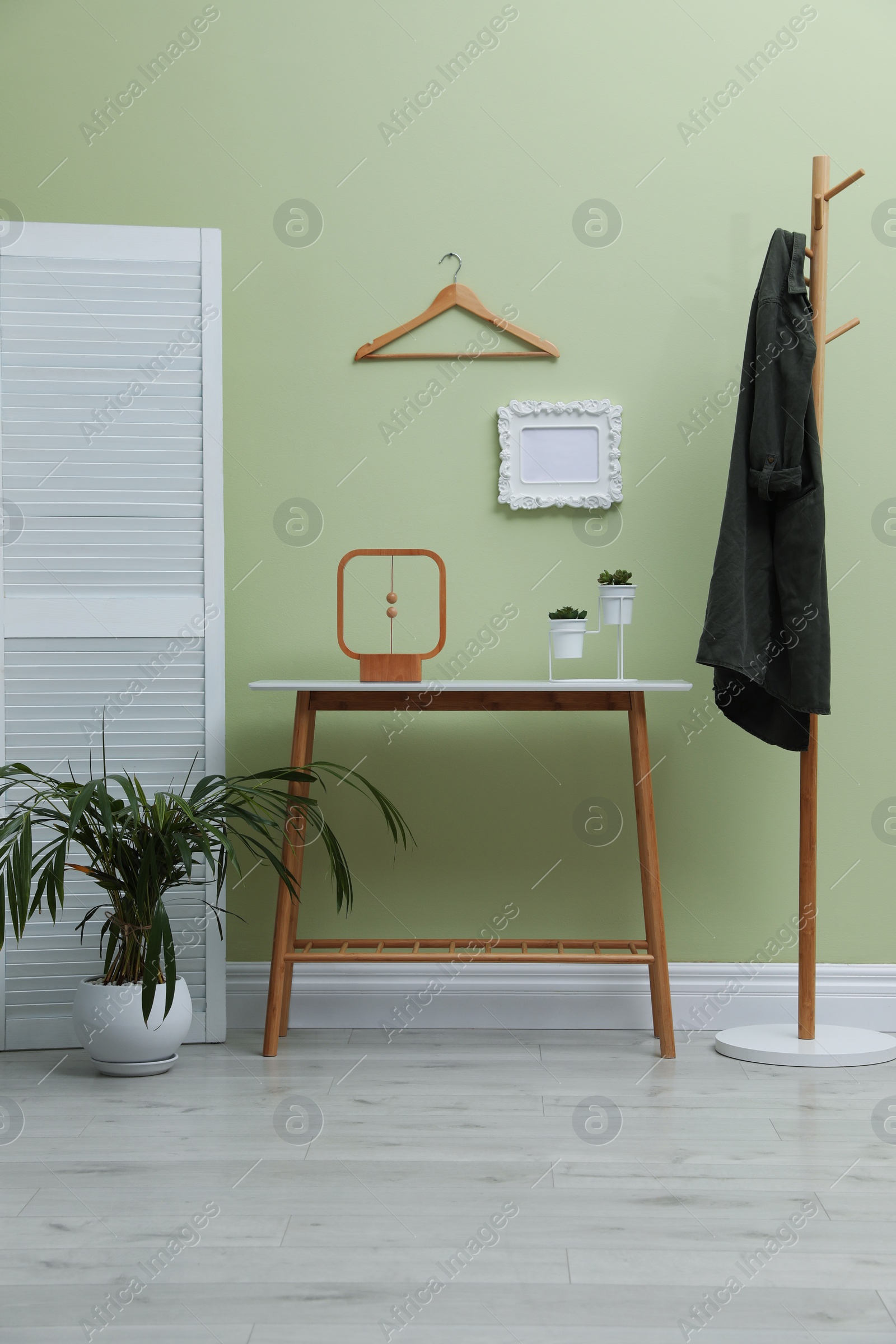 Photo of Console table with decor and coat stand in hallway. Interior design