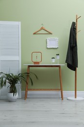 Photo of Console table with decor and coat stand in hallway. Interior design