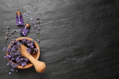 Photo of Essential oil and lavender flowers on dark grey background, flat lay. Space for text