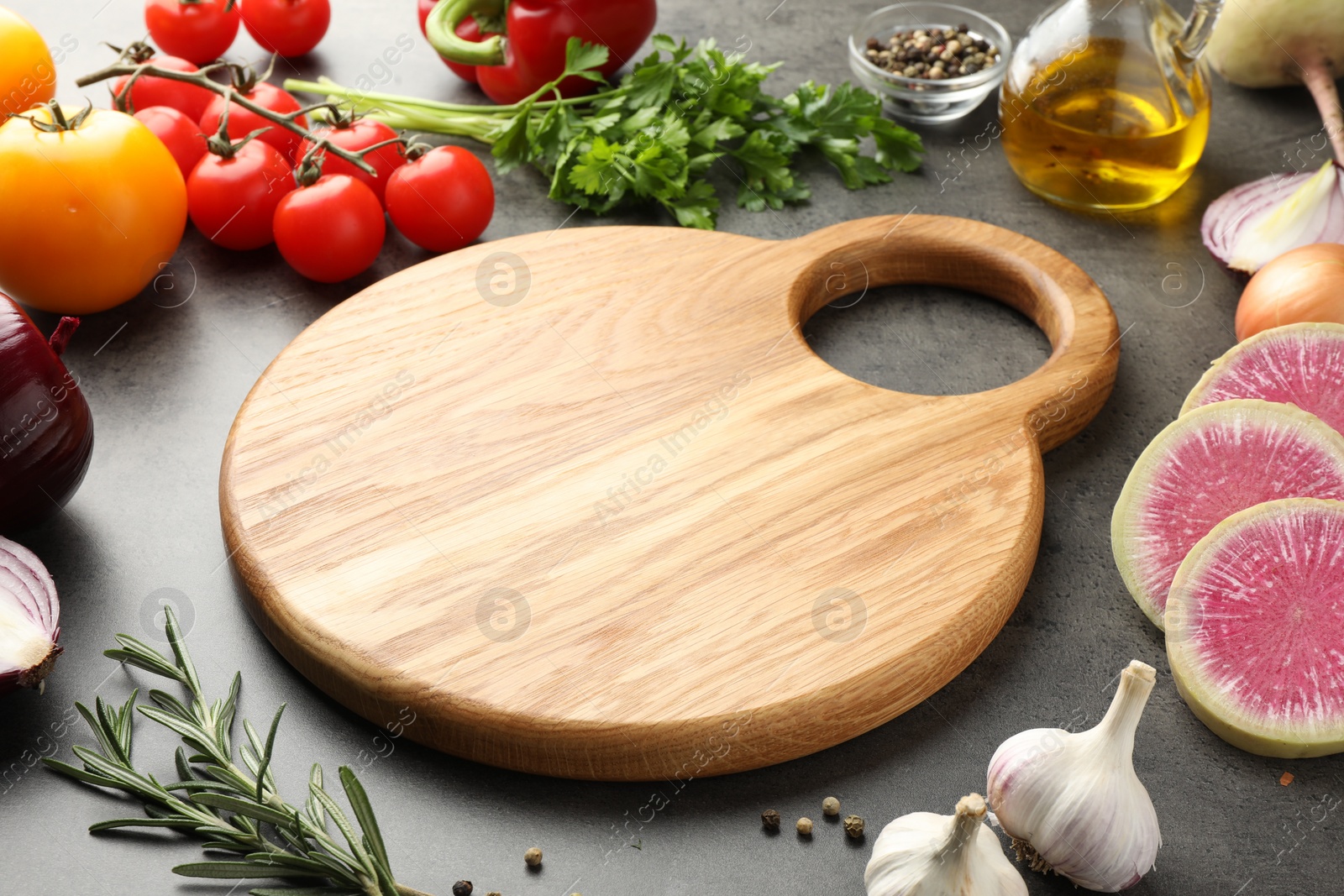 Photo of Wooden cutting board and products on dark table