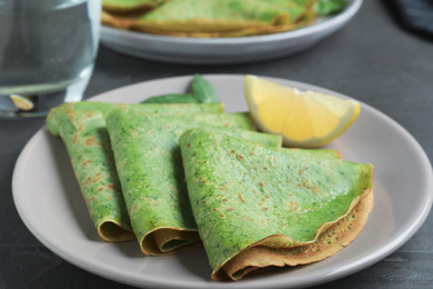 Tasty spinach crepes served on grey table, closeup