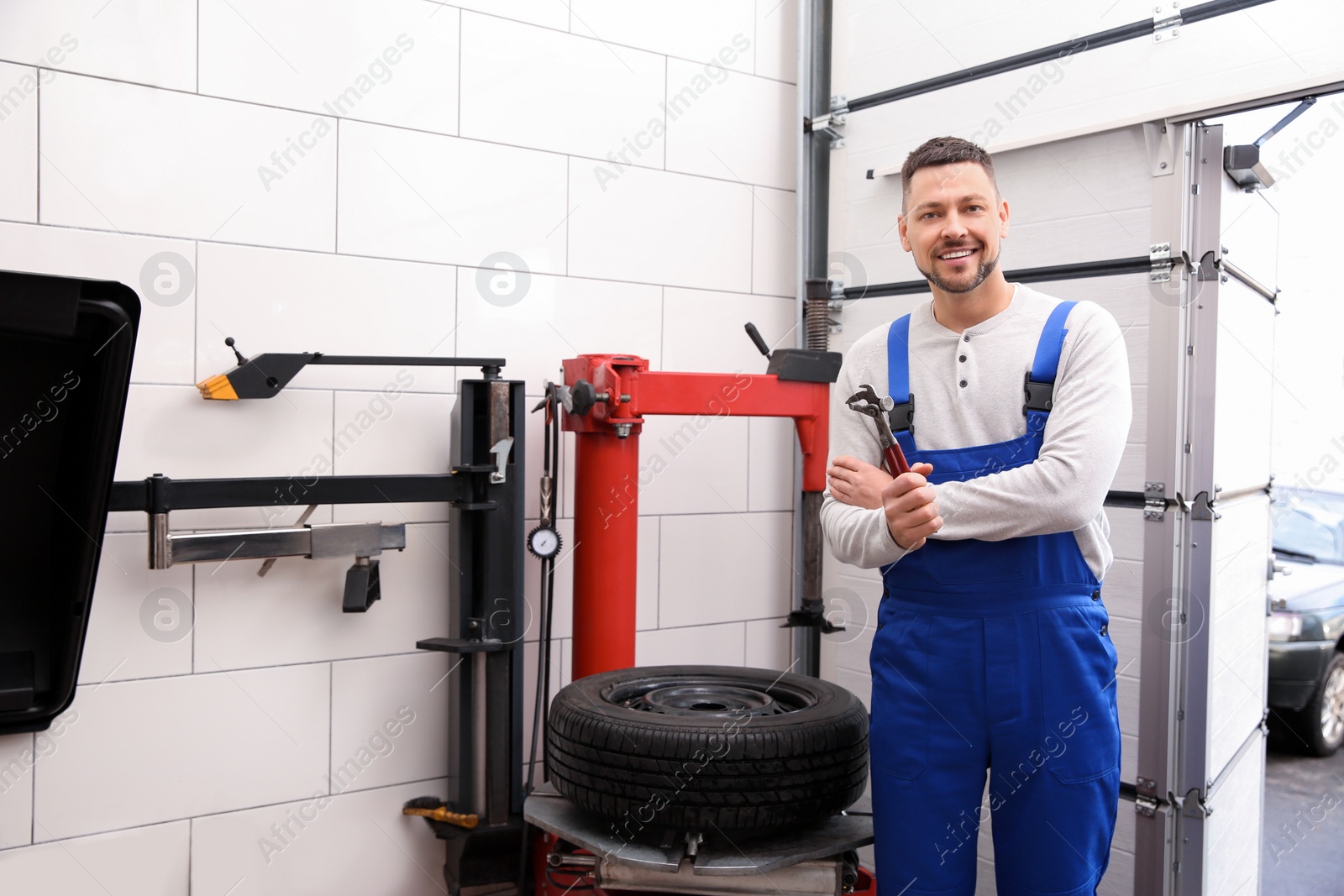 Photo of Man near tire fitting machine at car service