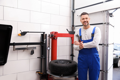 Photo of Man near tire fitting machine at car service