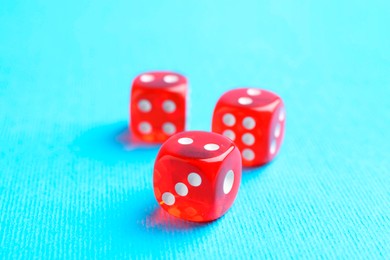 Photo of Three red game dices on light blue background, closeup. Space for text