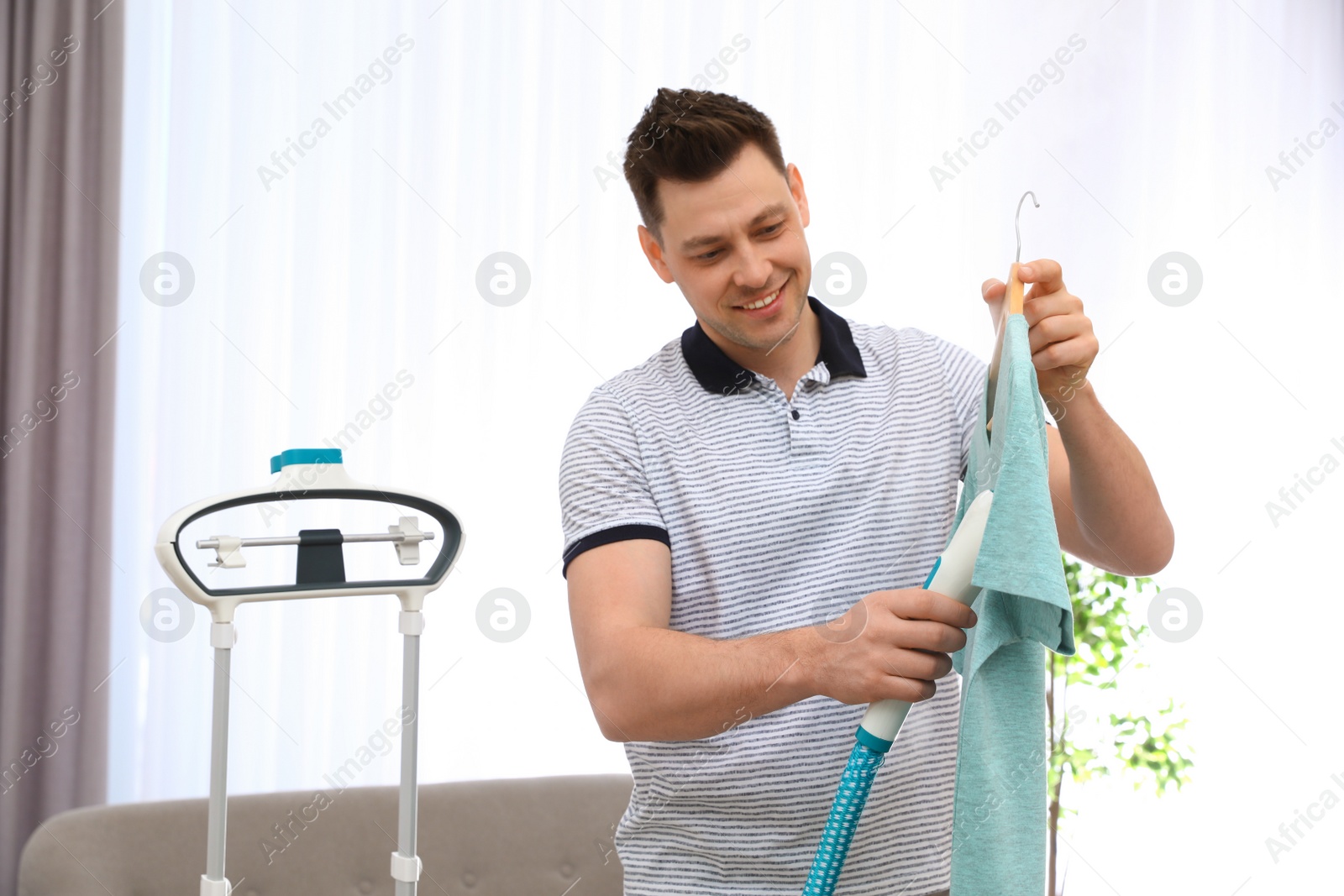 Photo of Man steaming his clothes in living room