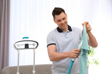 Man steaming his clothes in living room