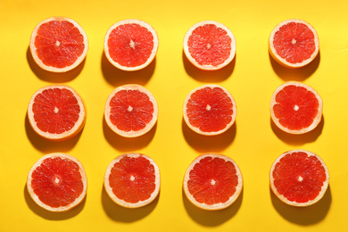 Photo of Flat lay composition with tasty ripe grapefruit slices on yellow background