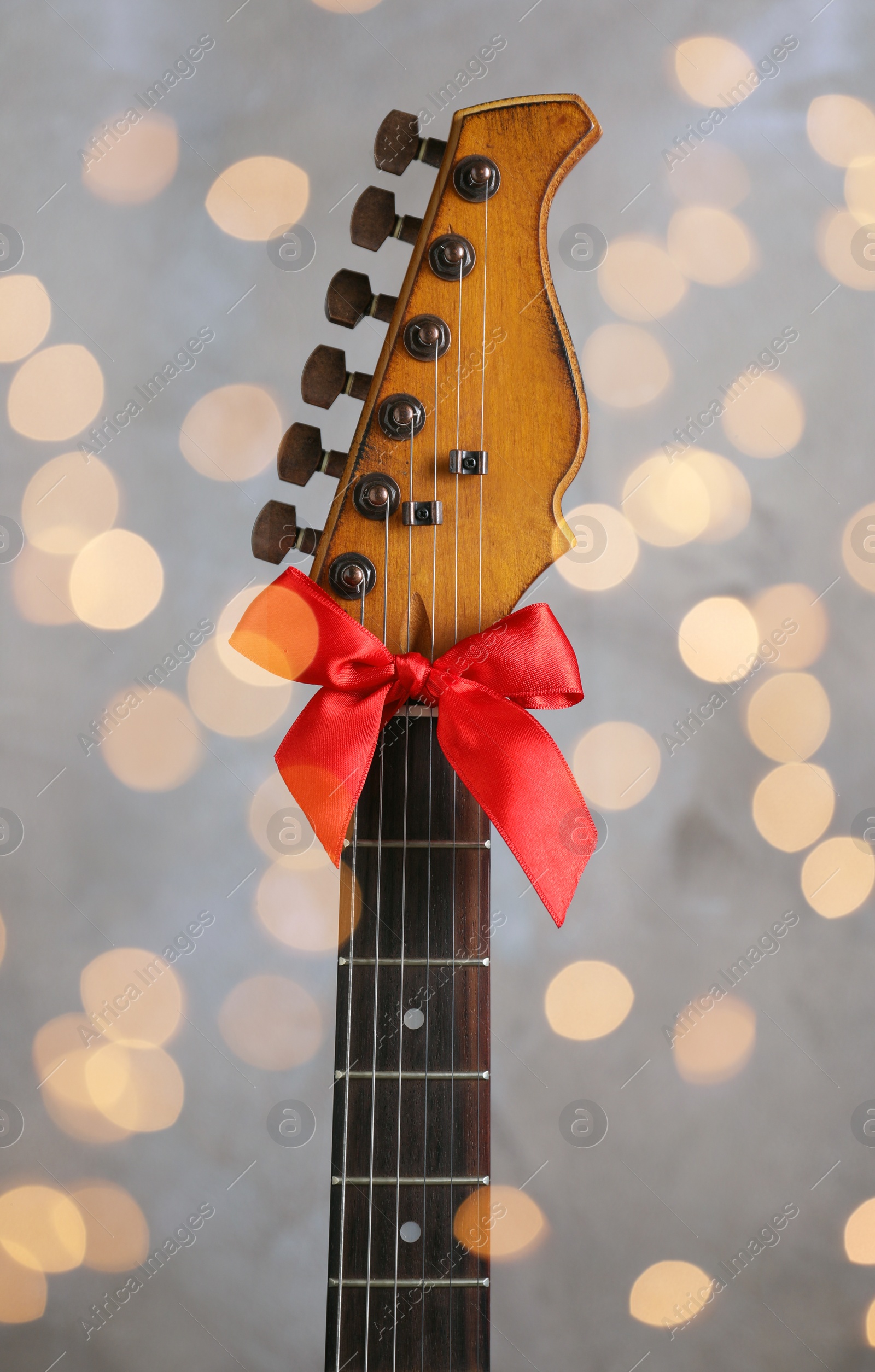 Photo of Guitar with red bow on grey background. Christmas music
