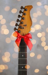 Photo of Guitar with red bow on grey background. Christmas music