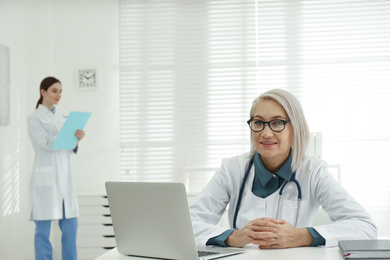 Photo of Portrait of mature female doctor in white coat at workplace